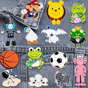 Assorted popular cartoon character lapel pins including yellow chick, frog, and sports (basketball, football) motifs on a dark background